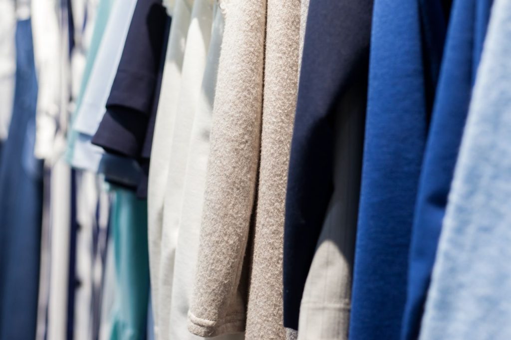 Collection of wear made of natural fabrics and hanging in shop with shiny light on blurred background