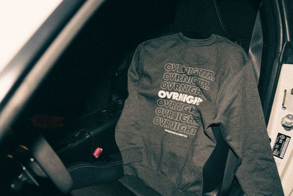 A stylish sweater with text design laid on a car seat, highlighting casual fashion style.